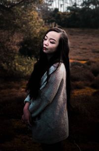 Close-up of young woman standing against trees