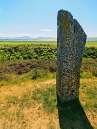 Wooden post on field against sky