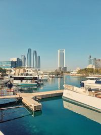 Boats in harbor against clear blue sky