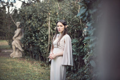 Portrait of fairy elf young woman standing by plants on land