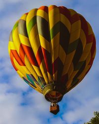Low angle view of hot air balloon flying against cloudy sky