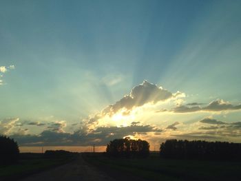 View of country road along landscape at sunset