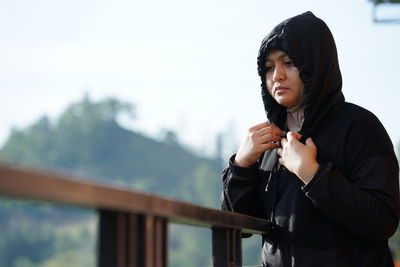 Young woman photographing while standing against mountain