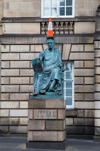 Traffic cone on statue against building