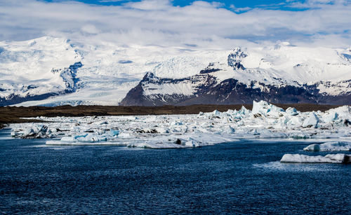 Scenic view of icebergs on sea against sky