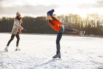 Two women ice skating on frozen lake