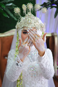 Beautiful muslim bride in a white dress with a pattern and showing a henna motif on her hand