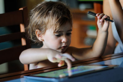 Close-up of girl using digital tablet on table