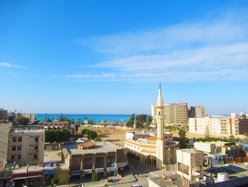 High angle view of buildings and sea against blue sky