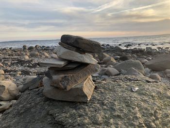 Rocks on beach against sky during sunset