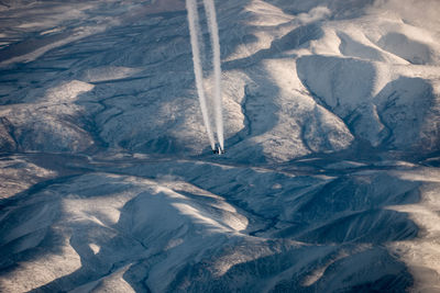 High angle view of snowcapped mountains with airliner