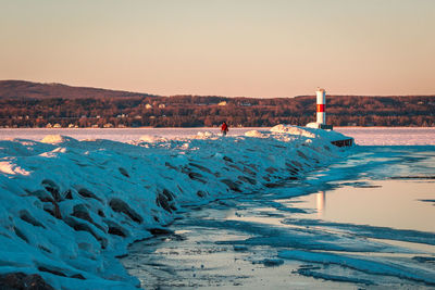 Tourist visiting a frozen lighthouse in petoskey michigan at sunset