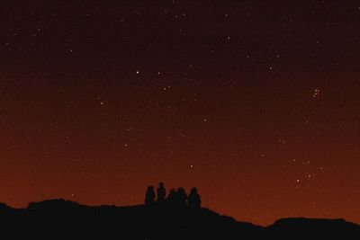 Silhouette people on mountain against star field at night