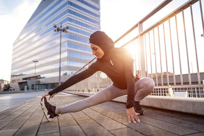 Side view of young woman on railing against sky