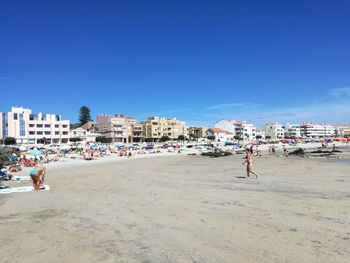 People on beach against clear blue sky