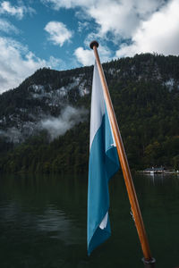 Scenic view of flag by lake against sky