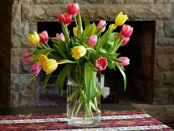 Tulip flowers in vase against fireplace at home