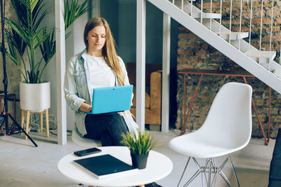 Young woman using phone while sitting on chair