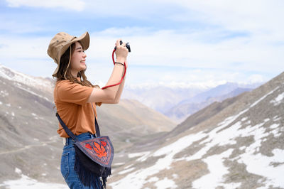 Full length of man photographing on mountain against sky