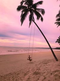 Full length woman swinging at f beach during sunset