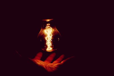 Close-up of burning candle over black background