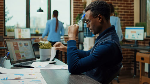 Side view of man using mobile phone while sitting at cafe