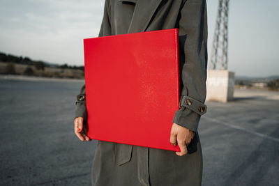 Woman holding red placard standing at road