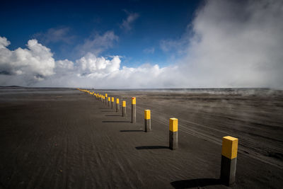 Wooden posts on beach against sky