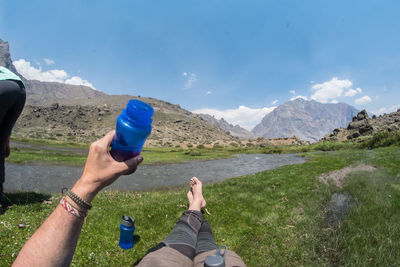 Low section of woman holding water against blue sky