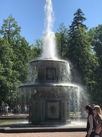 Fountain against trees and plants against sky