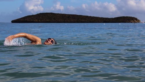 Woman swimming in sea against sky