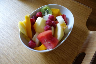 High angle view of fruit salad in bowl on wooden tray