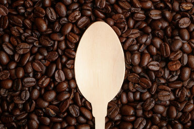 Close-up of wooden spoon on roasted coffee beans