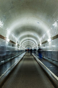 Rear view of people walking in subway tunnel