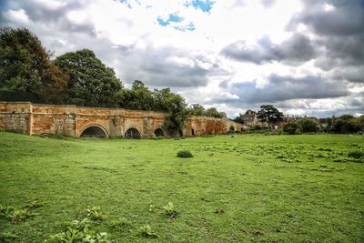 Arch bridge on field against sky