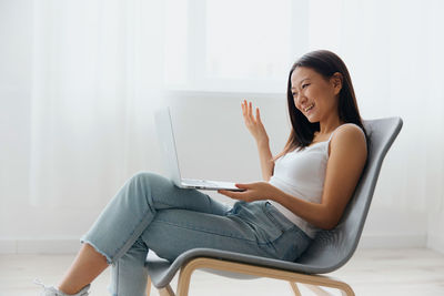 Young woman using laptop while sitting on sofa at home