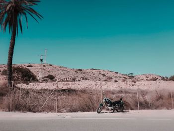 Man by car on landscape against clear blue sky