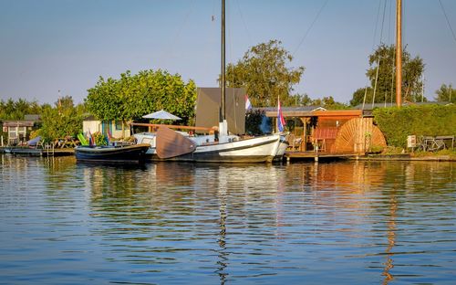 Sailboats moored in river against sky