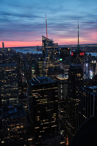 Illuminated buildings in city against sky during sunset