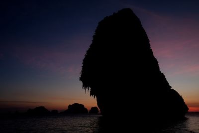 Silhouette rock in sea against sky during sunset