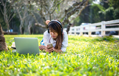 Young woman using mobile phone in field