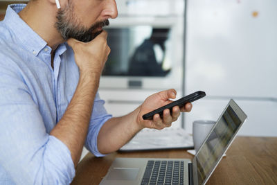 Midsection of businessman using laptop on table