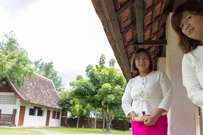 Woman standing by tree against building
