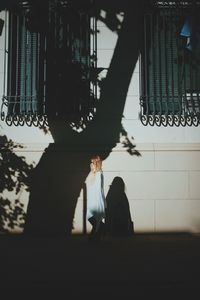 Side view of woman standing by wall with shadows