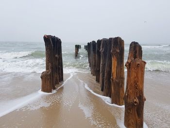 Panoramic view of wooden post on beach against clear sky