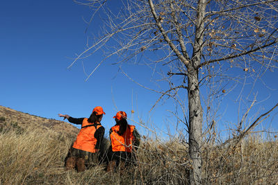 Two female hunters look for elk in a meadow in colorado