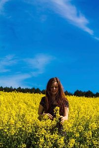 Young woman standing amidst flowers on field