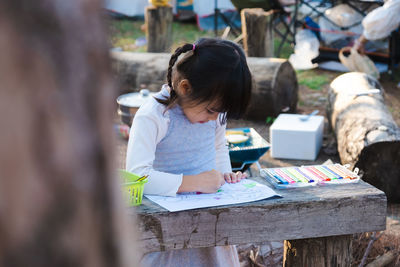 Cute girl drawing on paper outdoors