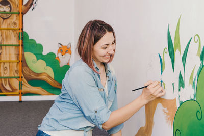 Woman painting wall at home