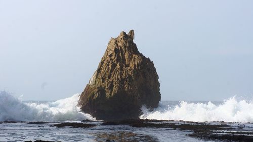 Rock formation in sea against sky